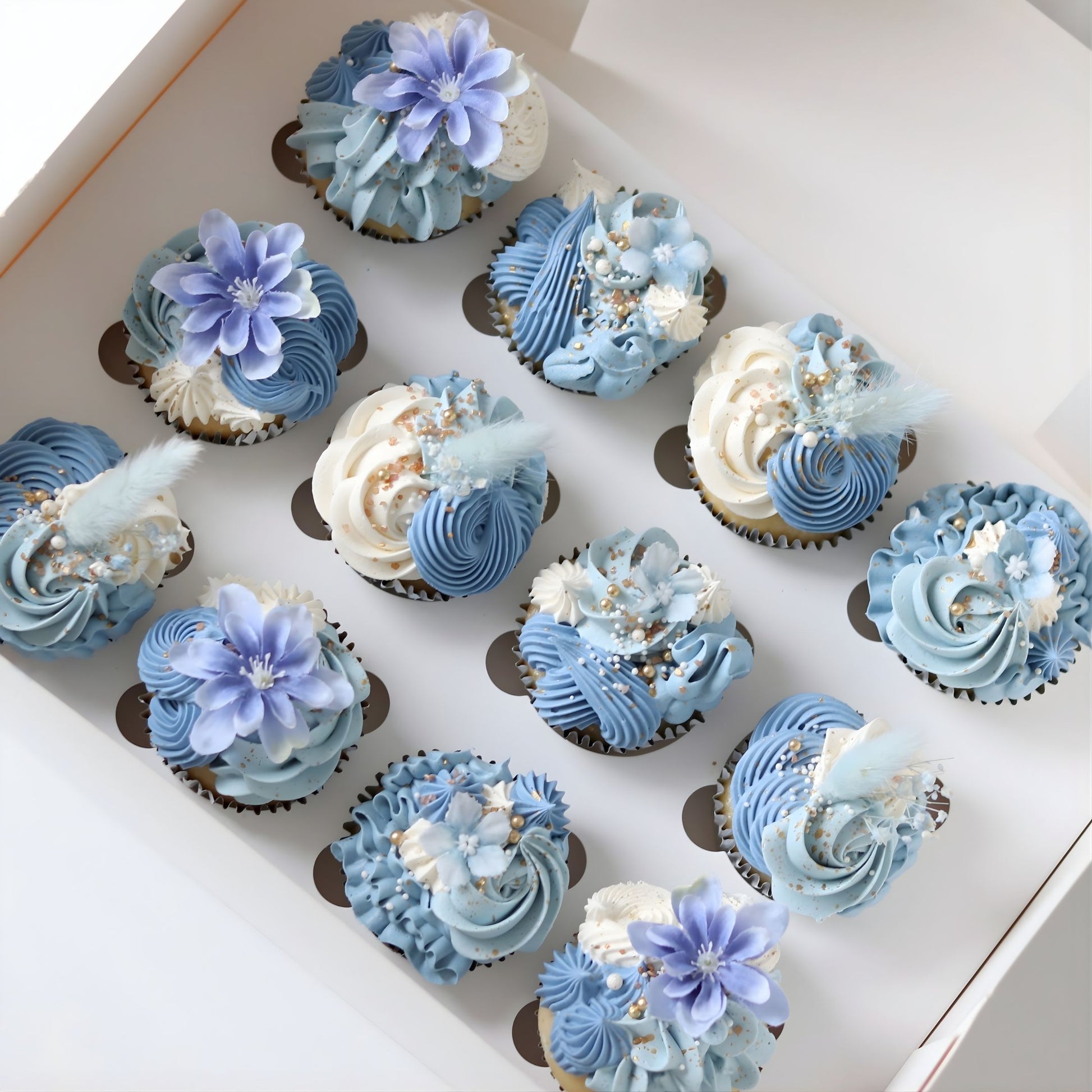 Blue and white boho cupcakes decorated with delicate piping, flowers and sugar pearls