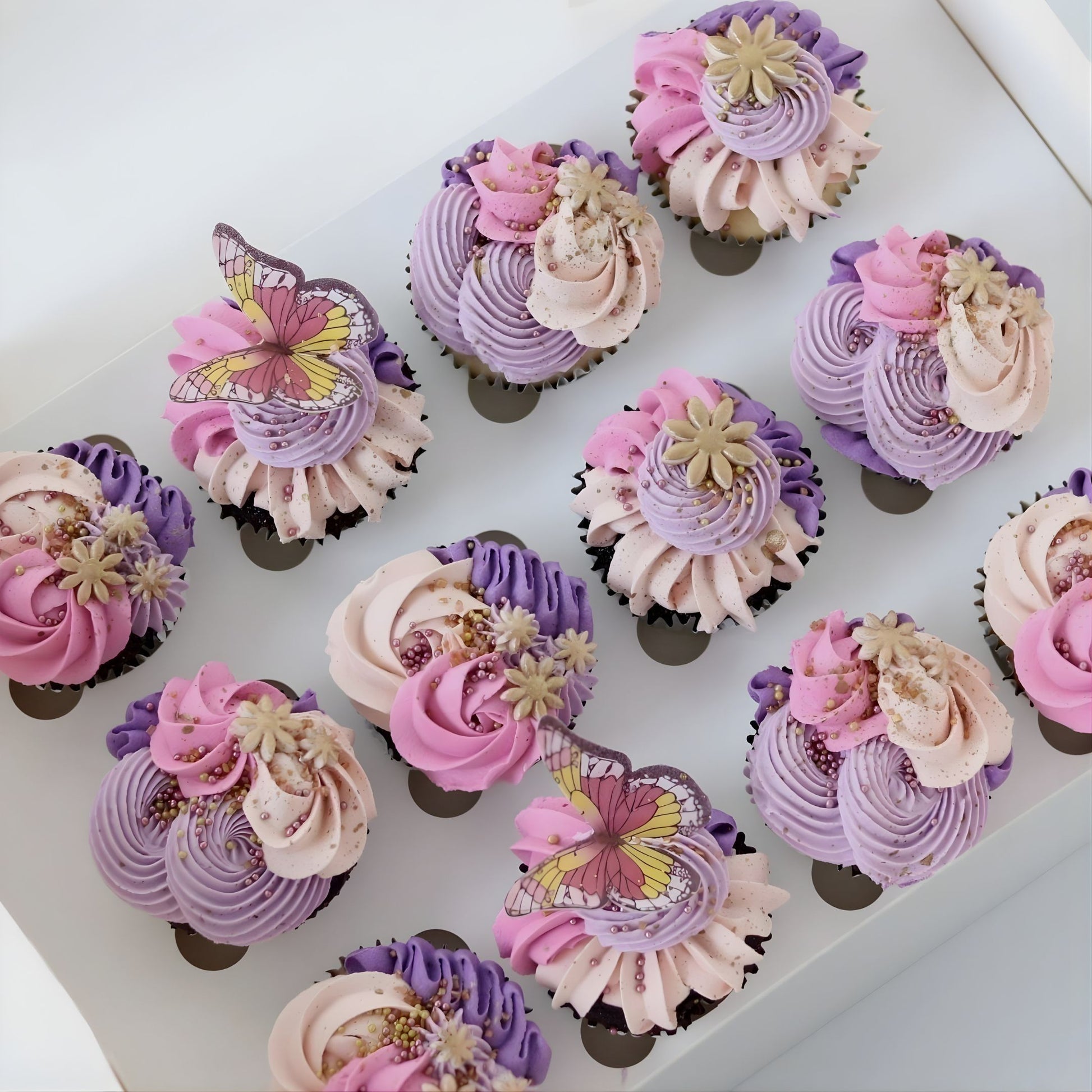 Pink and purple enchanted theme cupcakes decorated with delicate piping, flowers, butterflies, sugar pearls