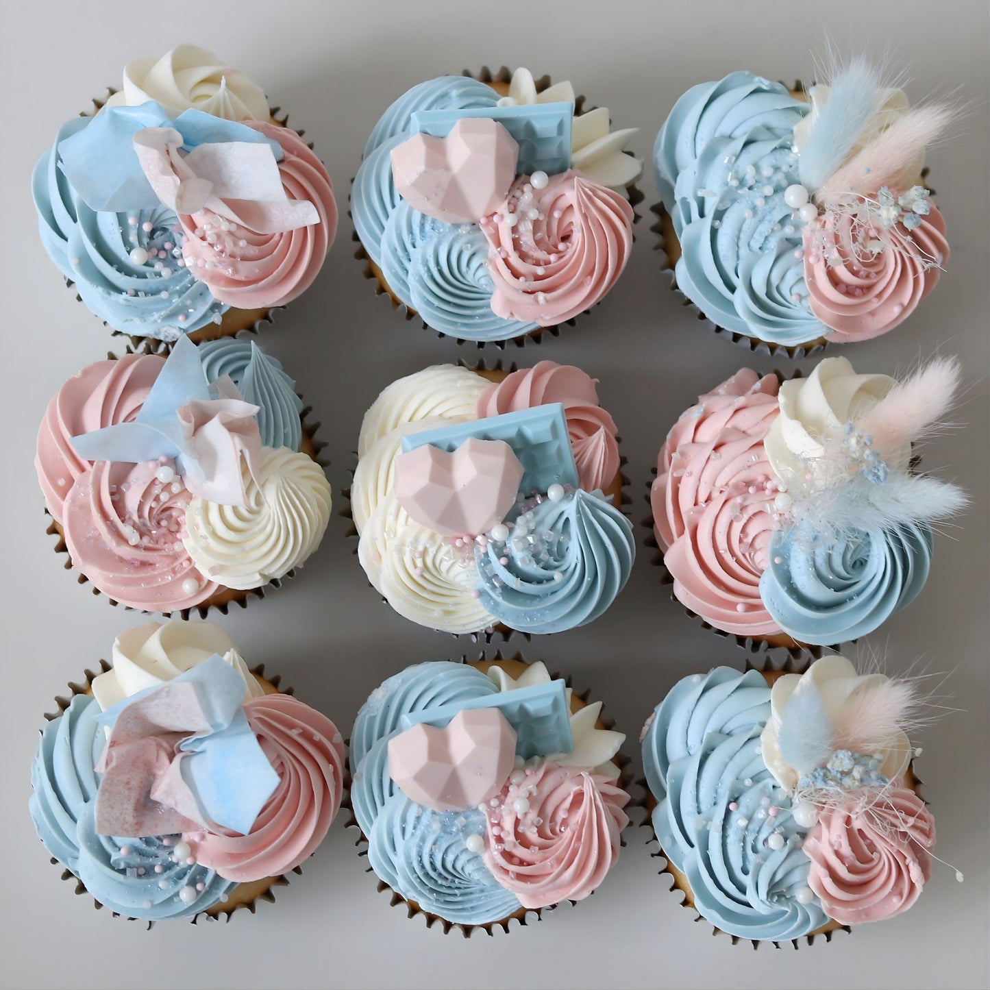 Pink and blue gender reveal cupcakes decorated with delicate piping, flowers and sugar pearls