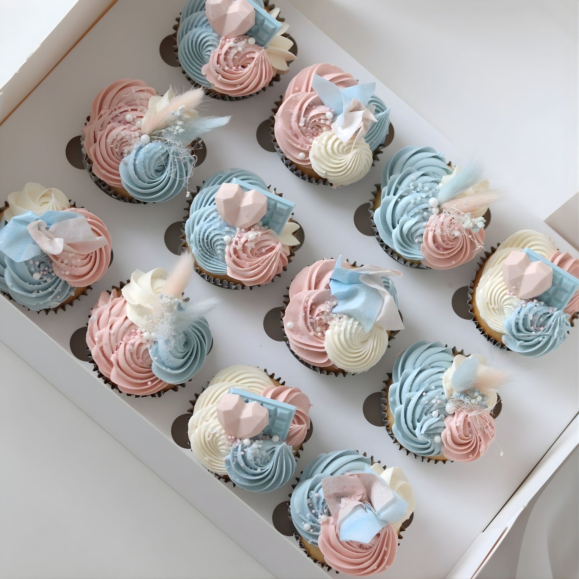 Pink and blue gender reveal cupcakes decorated with delicate piping, flowers and sugar pearls