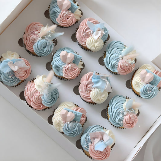 Pink and blue gender reveal cupcakes decorated with delicate piping, flowers and sugar pearls