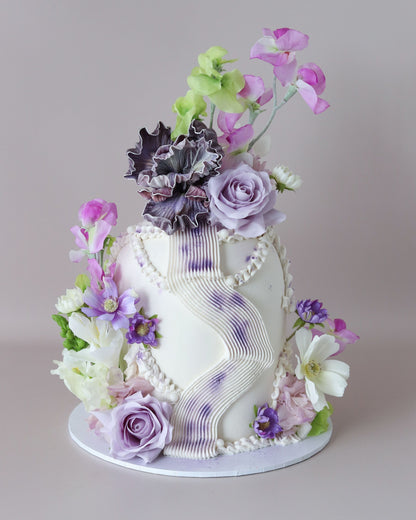 A modern and striking dome-shaped showstopper featuring a purple and green floral palette, organic squiggles and shimmering accents.